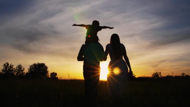 Parents adultes avec petit fils marchant au coucher du soleil — Video