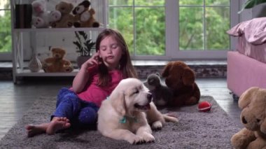 Sevimli kız yerde oturan köpek yavrusu ile oynarken
