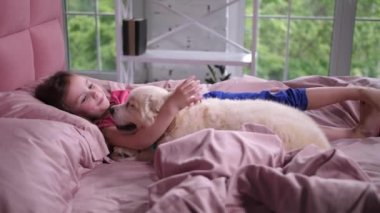 Tatlı küçük kız yatakta yatan köpek yavrusu konuşuyor