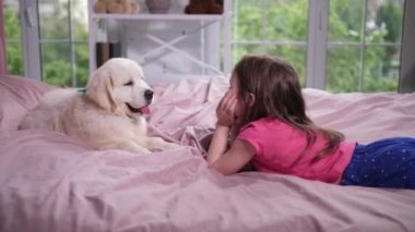 Küçük kız köpek yavrusu ile rahat yatakta yatan
