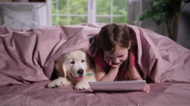 Küçük kız yatakta köpek yavrusu ile karikatür izliyor