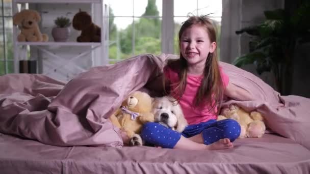 Vreugdevolle kind verstopt onder deken met puppy huisdier — Stockvideo