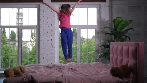Fröhliche süße kleine Mädchen springen auf Bett im Kinderzimmer — Stockvideo