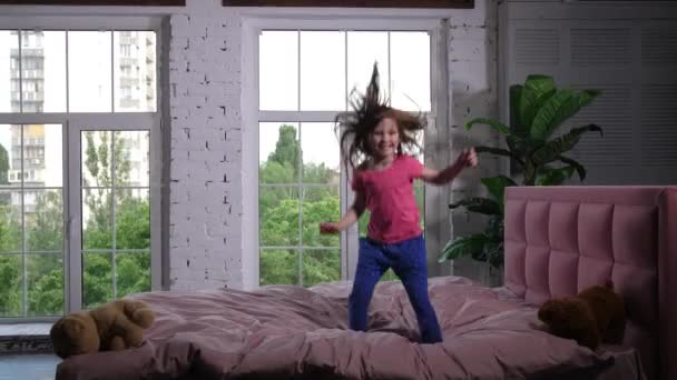 Glückliches kleines Kind springt auf kuscheliges Bett im Schlafzimmer — Stockvideo