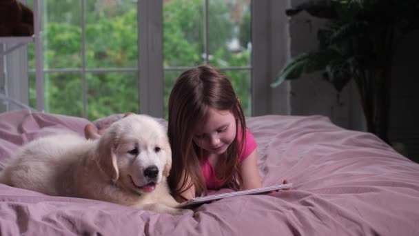 Vreugdevolle kind kijken naar YouTube op tablet met puppy — Stockvideo