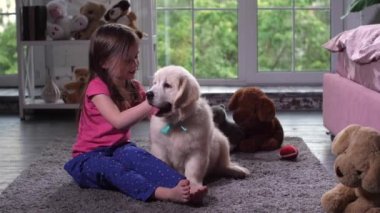 Evde halı üzerinde oturan köpek yavrusu ile oynayan çocuk