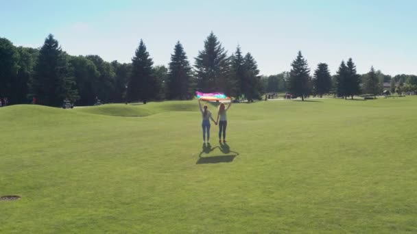 Drone vuelo sobre lesbiana pareja holding lgbt bandera — Vídeos de Stock