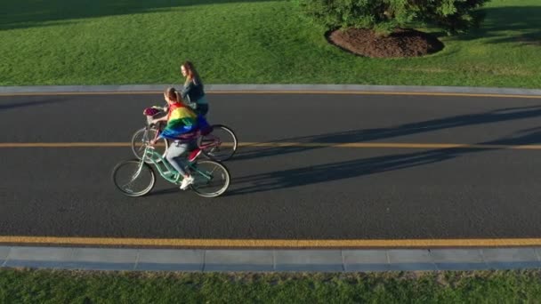 Antenn sida vy över unga HBT-par ridning cyklar — Stockvideo