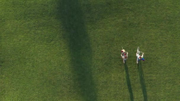 Drone shot de couple lgbt faisant du vélo à travers la pelouse du parc — Video