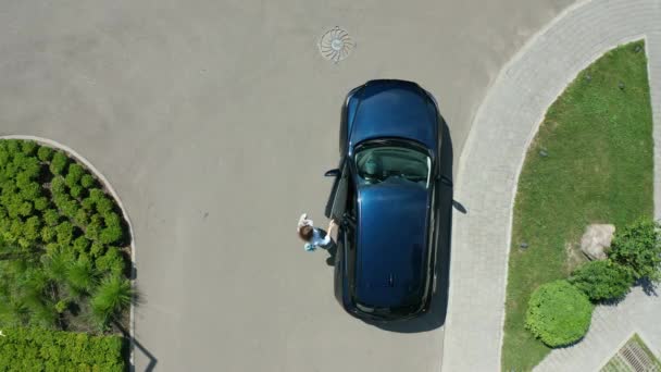 Снимок с беспилотника женщины, идущей из машины в отель — стоковое видео