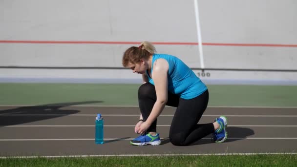スタジアムで靴ひもを結ぶアクティブな脂肪の女性ランナー — ストック動画