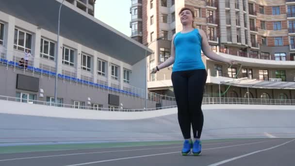 Sobrepeso femenino saltar cuerda en campo de deportes — Vídeo de stock