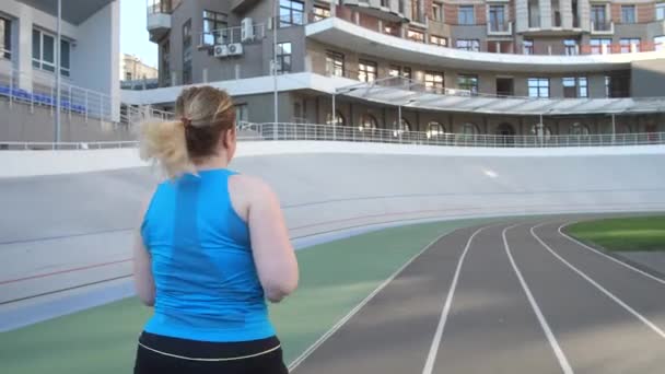 Excesso de peso feminino jogging ao longo da pista do estádio — Vídeo de Stock