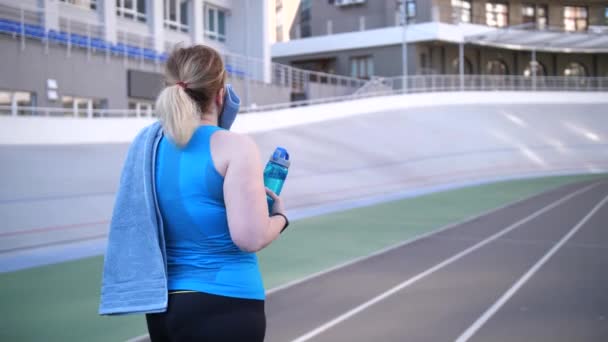 Além de tamanho feminino caminhando ao longo da pista depois de correr — Vídeo de Stock