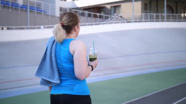 Плюс розмір жінка бігун ходить з соковитим напоєм — стокове відео