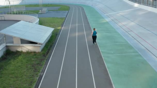 Vista aérea de hembra de tamaño grande corriendo en pista — Vídeos de Stock