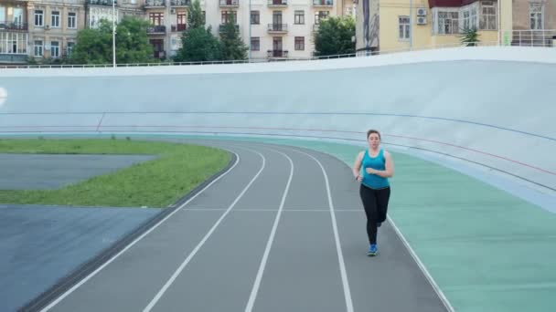 Drone disparo de la mujer gorda activa trotando en la pista — Vídeo de stock