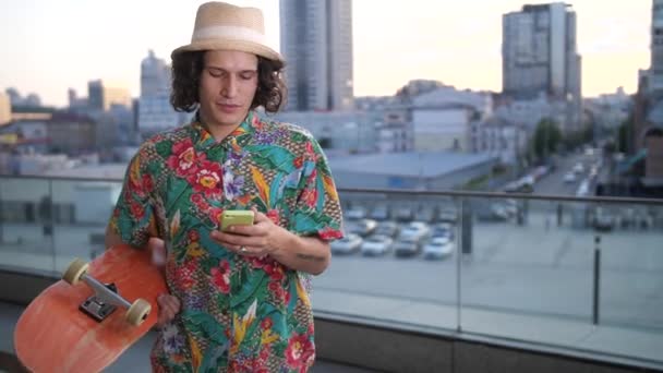 Male skater using phone while walking with board — Stock Video