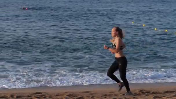 Blonde Läuferin trainiert am Sandstrand — Stockvideo