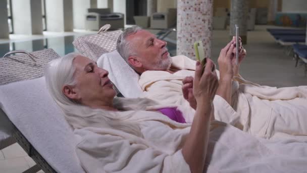 Happy aging par med hjälp av telefoner avkopplande på hotellet — Stockvideo