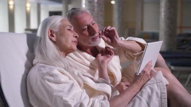 Старая пара разговаривает онлайн на планшете в отеле — стоковое видео