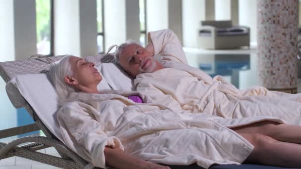 Стара пара говорить, лежачи на шезлонгах в готелі — стокове відео
