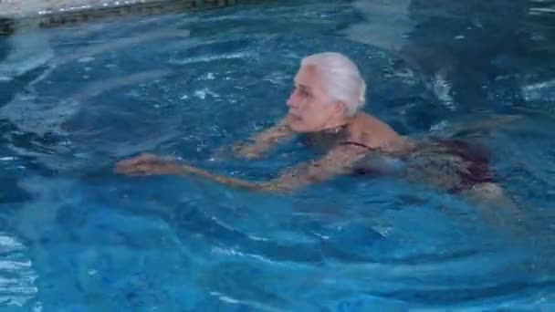 Happy elderly woman swimming in pool of spa hotel — Stock Video