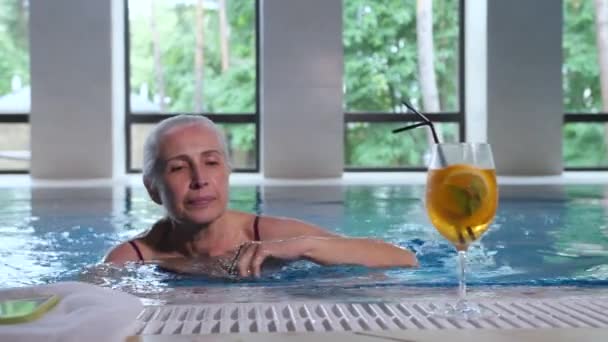 Reife Frau schwimmt in Wellness-Hotel zur Poolseite — Stockvideo