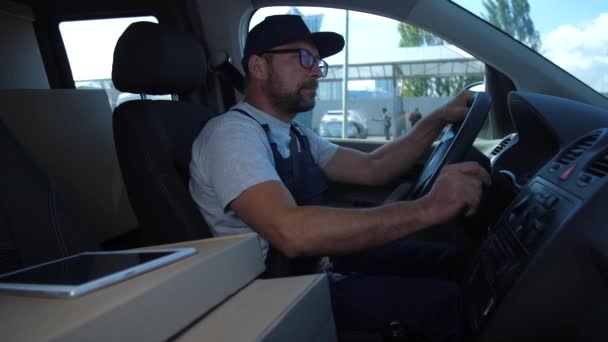 Levering man in Cap controle route zittend in de auto — Stockvideo