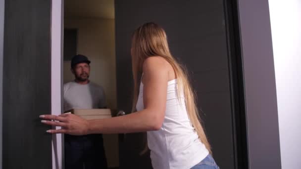 Женщина открывает дверь в квартиру доставщику пиццы — стоковое видео