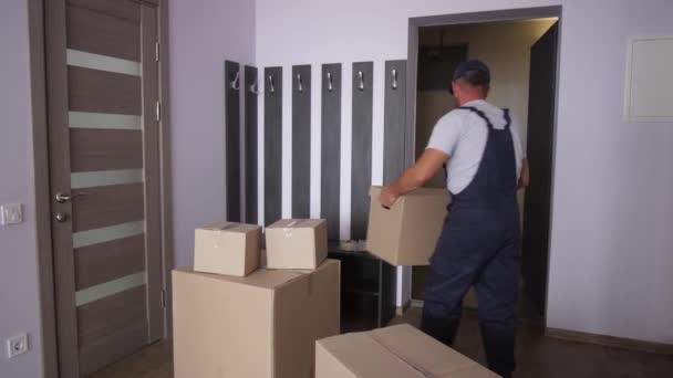 Trabajador en uniforme sacando cajas del apartamento — Vídeo de stock