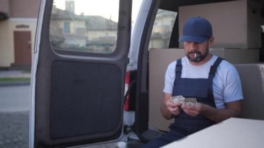 Bagaj kenarında oturan teslimatçı sayma ipuçları