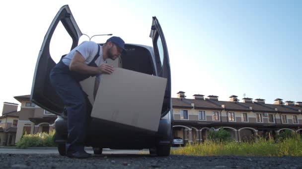 Сотрудник службы доставки забирает коробки из фургона — стоковое видео