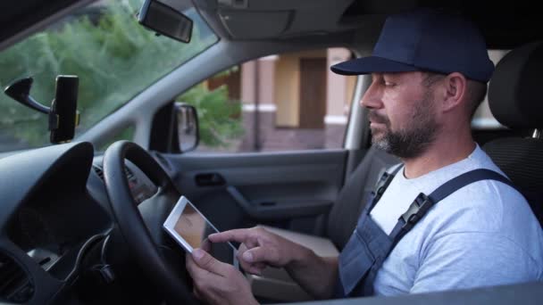 Entrega hombre comprobación de pedidos en la tableta en el coche — Vídeos de Stock