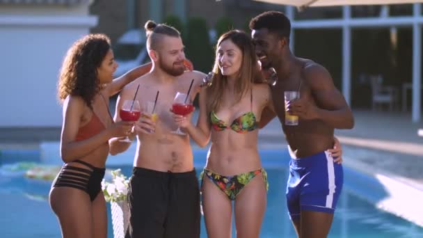 Joyful amigos multirraciais beber suco por piscina — Vídeo de Stock