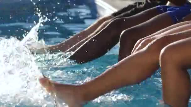 Ноги разных друзей в воде бассейна — стоковое видео