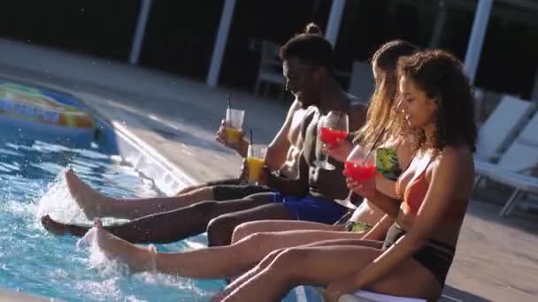 Vrolijke vrienden schoppen water spetteren in zwembad — Stockvideo