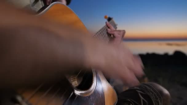 밤에 캠프 파이어 근처에서 기타를 연주하는 남성 손 — 비디오