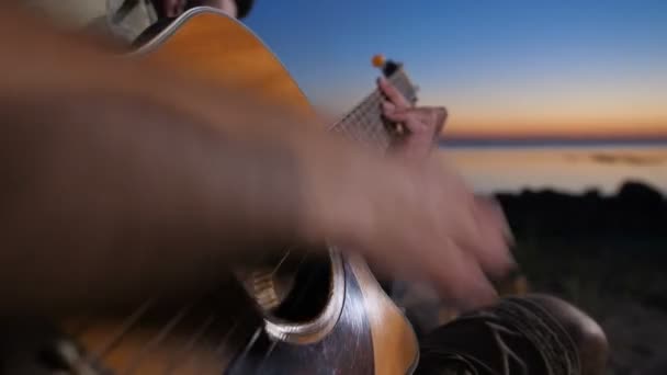 Geceleri kamp ateşi yakınında gitar çalan erkek eller — Stok video