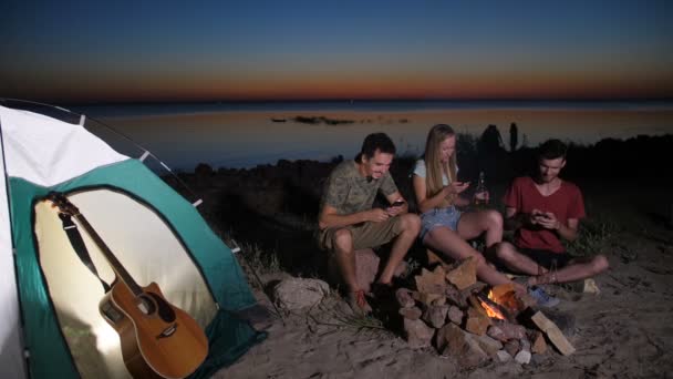 Veselé turistické přátele relaxační nedaleko táborního ohně — Stock video