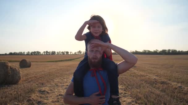 Dad carrying son on shoulders walking across field — Stock Video