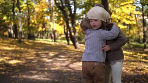 Милые младшие брат и сестра обнимаются на природе — стоковое видео