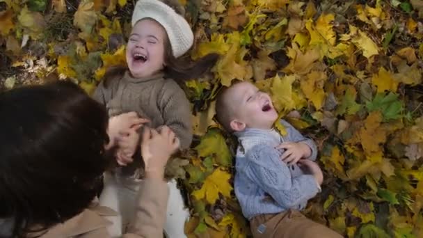 Игривая мама щекочет счастливых маленьких детей в парке — стоковое видео