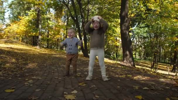 Χαρούμενα μικρά αδέλφια χορεύουν αστεία στο δρομάκι του πάρκου — Αρχείο Βίντεο