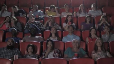 Sinema salonunda korku izleyen çeşitli izleyiciler