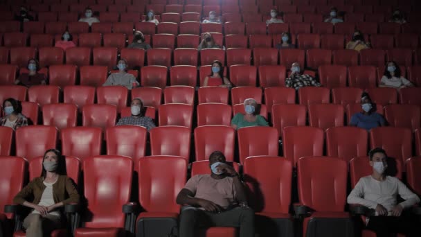 Diversos espectadores mascarados assistindo filme no cinema — Vídeo de Stock