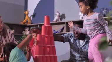 Karışık ırk kızları aileleriyle yatakta oynuyorlar.