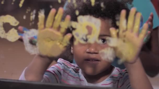 Симпатичные девушки смешанной расы делают отпечатки рук на окне — стоковое видео