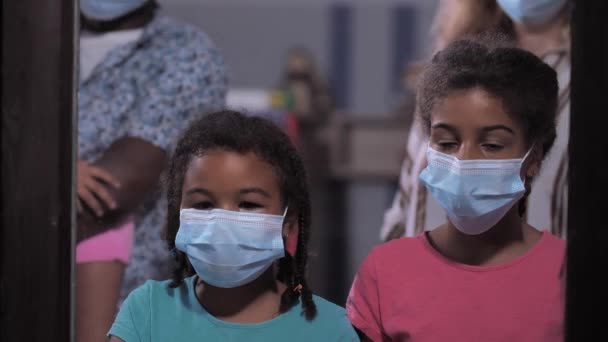 Meninas encaracoladas em máscaras faciais com os pais pela janela — Vídeo de Stock
