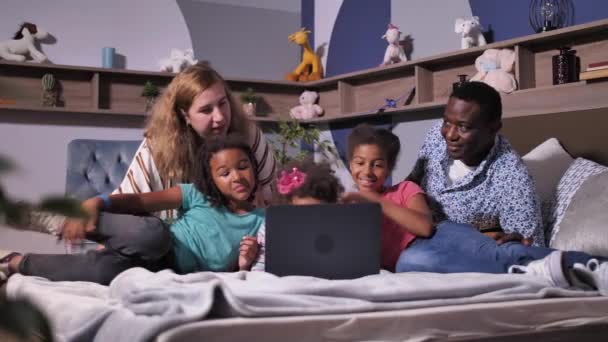 Familia feliz usando el ordenador portátil de chat en línea en la cama — Vídeos de Stock